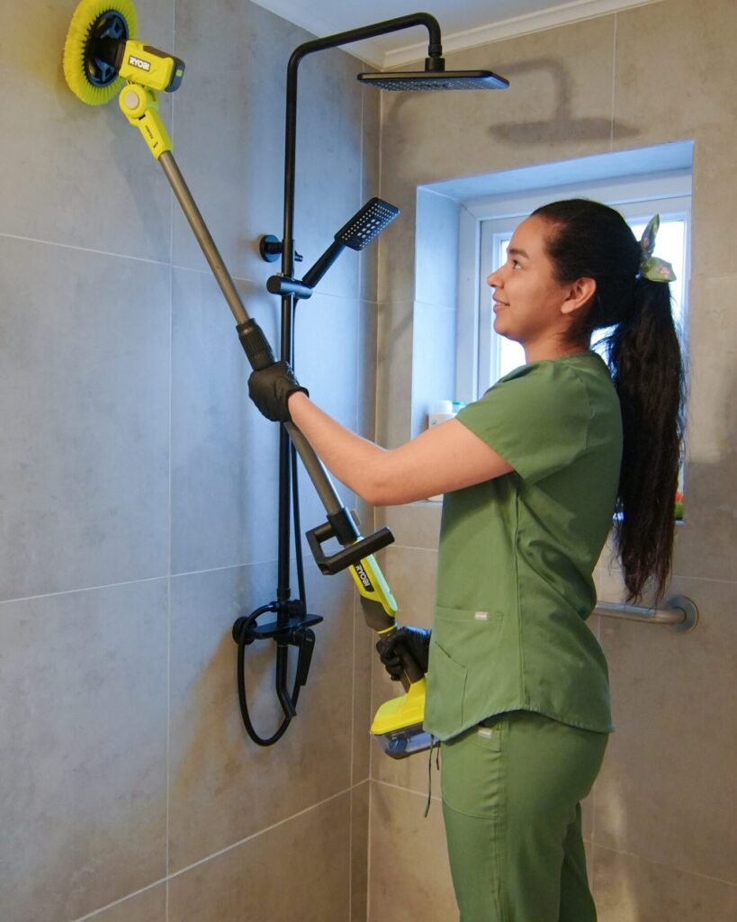 Profesional KLÁZA limpiando la ducha con cepillo eléctrico